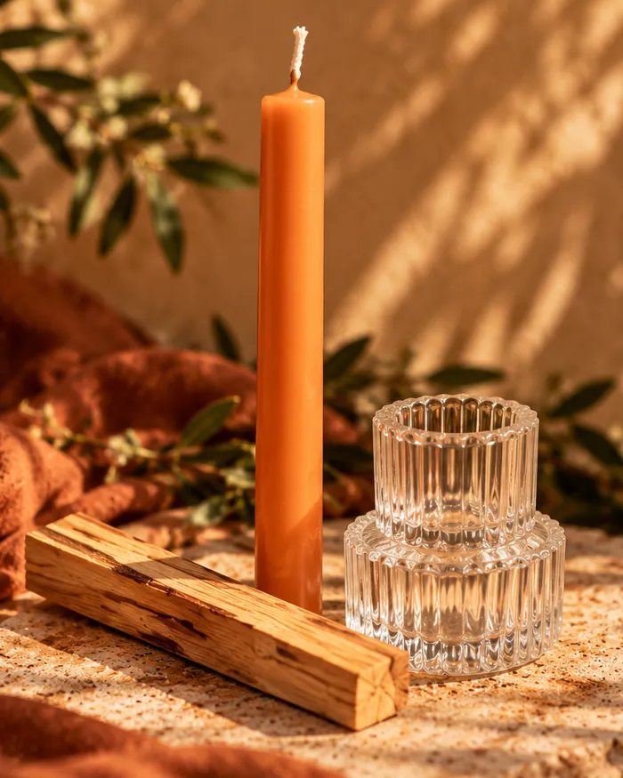 Close view of the 6 inch orange taper candle beside olive branches